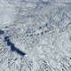 An iceberg carving a path through the sea ice near the Antarctic Peninsula. Photo: NASA/Nathan Kurtz